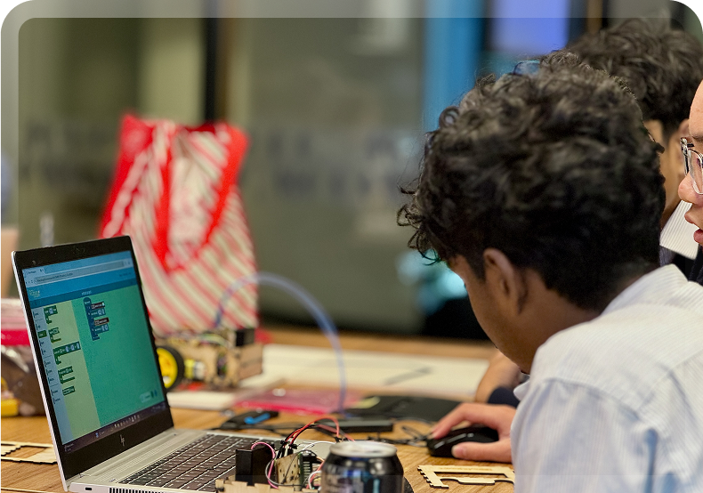 A group of students focused on a laptop with the Ro/Box block code editor open